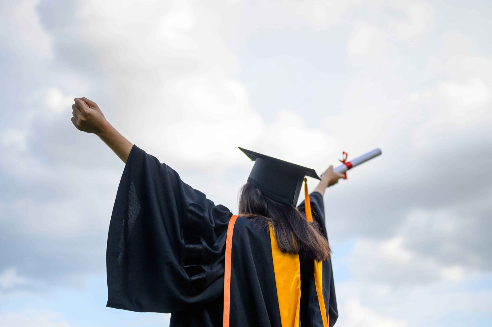 Long haired female students wearing black ruffle dresses expressing joy graduation university.